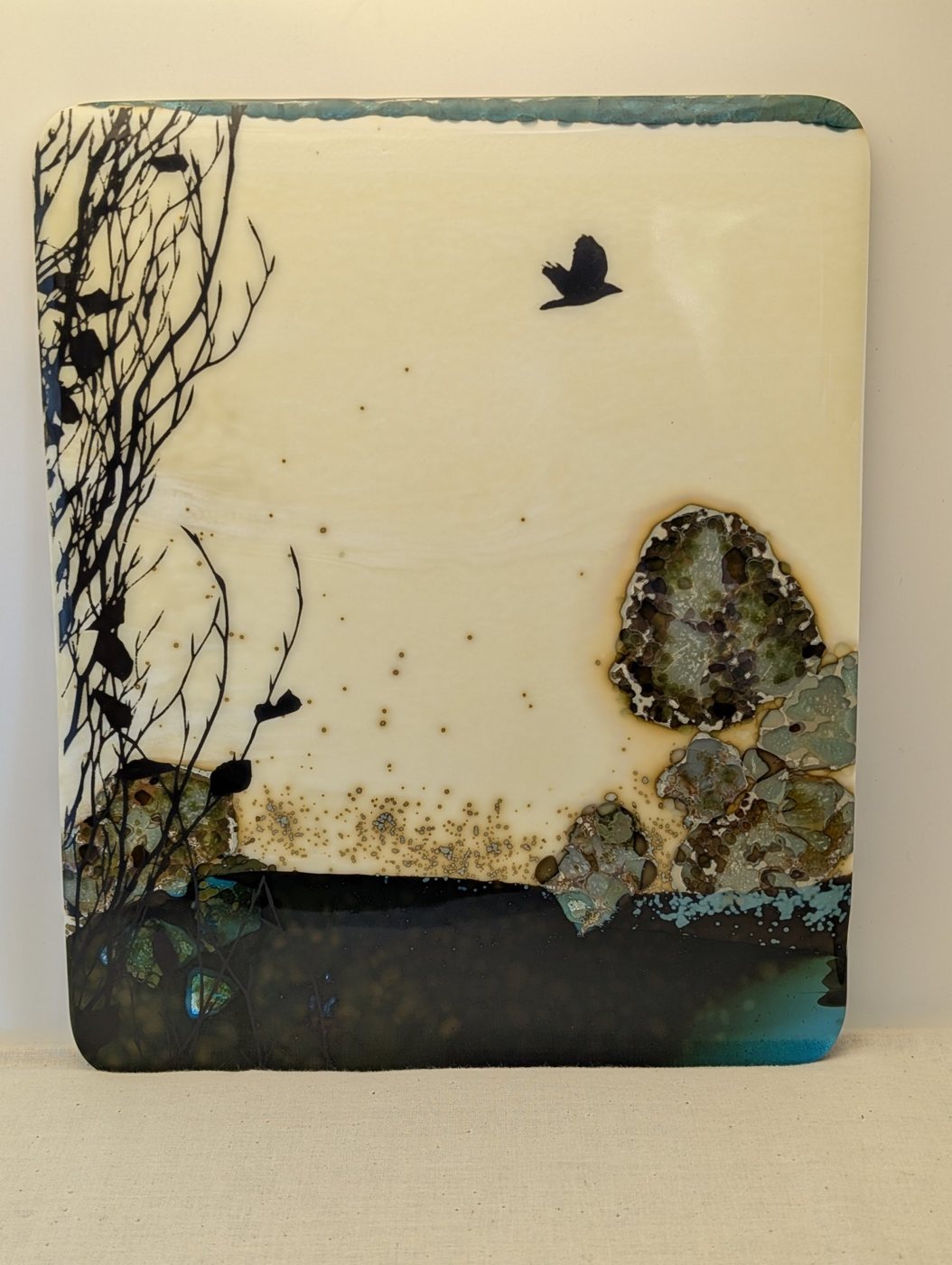 Fused glass panel with a bird in flight over stones